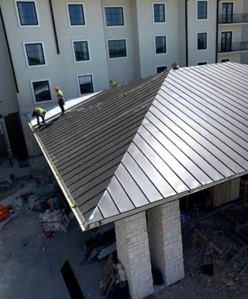 Crew installing standing seam metal roof panels on a commercial project in Auburn